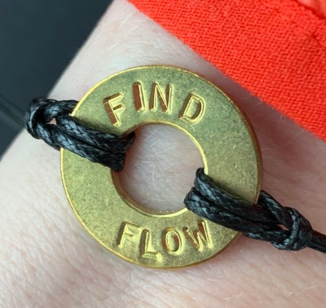 Flat gold ring with an imprint: "FIND FLOW"